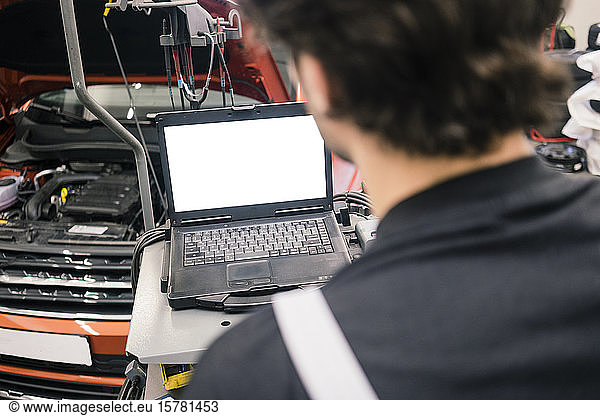 Car mechanic in a workshop using laptop