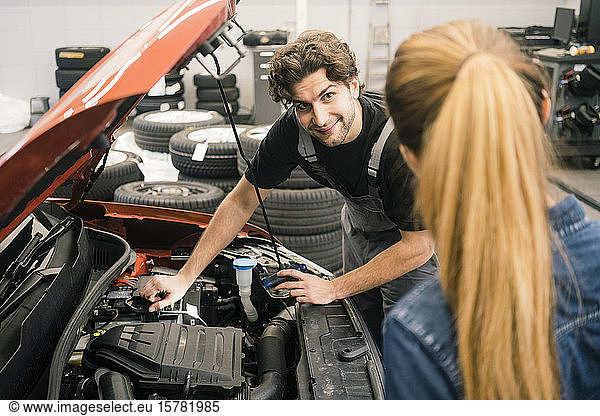 Car mechanic looking at client in workshop
