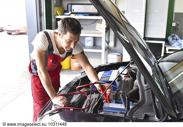 Car mechanic working in repair garage  reloading car battery