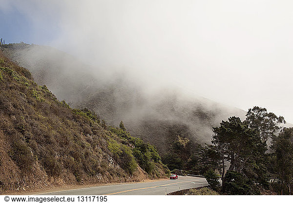 Car moving on mountain road during foggy weather