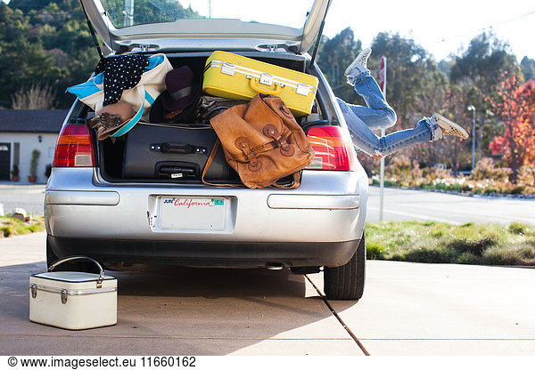 Car packed with luggage and legs of woman sticking out of car window