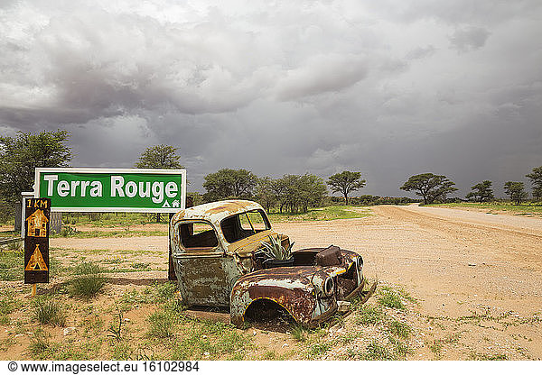 Car wreck at the entrance gate of the Terra Rouge guest farm at the C 15 gravel road. During the rainy season with green vegetation. Kalahari Desert  Hardap Region  Namibia.