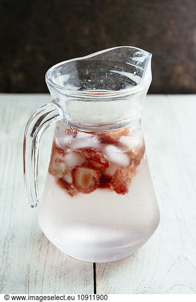 Carafe with sparkling water  ice cubes and slices of strawberries