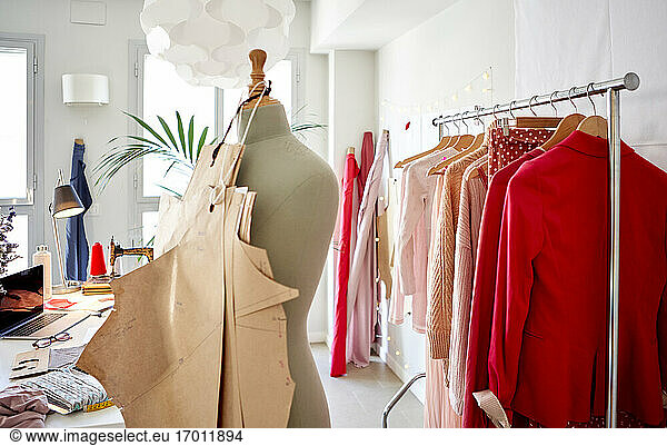 Cardboards hanging on dressmaker's model against clothes rack at design studio