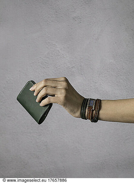 cardholder in a girl's hand with vintage watch. long leather strap
