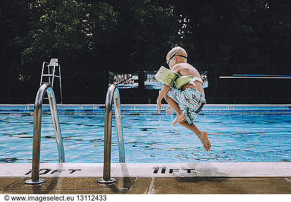 Carefree boy jumping into swimming pool