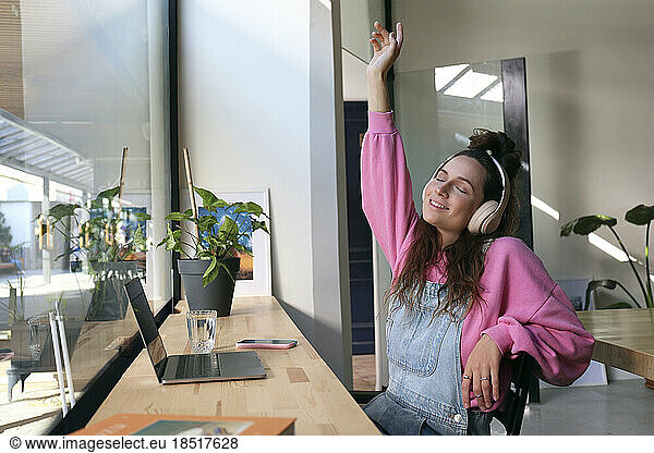 Carefree freelancer enjoying music through headphones at cafe