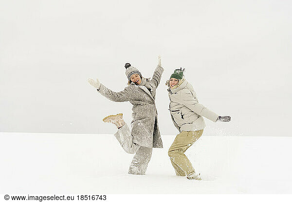 Carefree friends dancing together on snow in winter