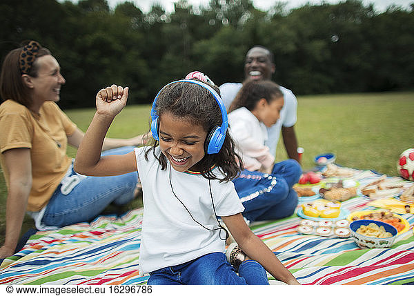 Carefree girl listening to music with headphones on picnic blanket