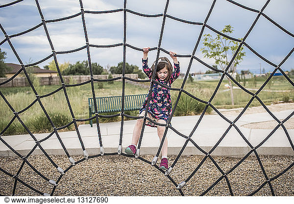 Carefree girl playing on rope at playground