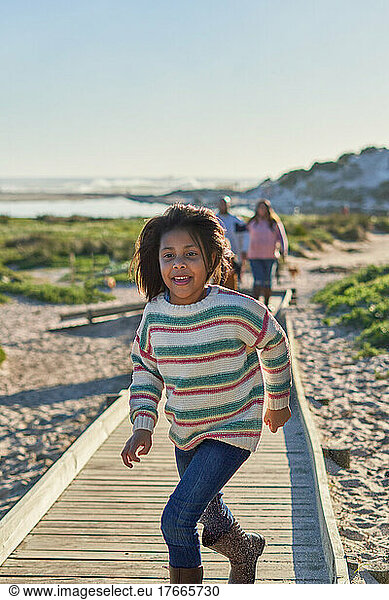 Carefree girl running on sunny beach boardwalk