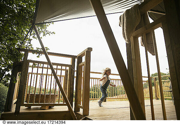 Carefree girl running on wooden cabin balcony