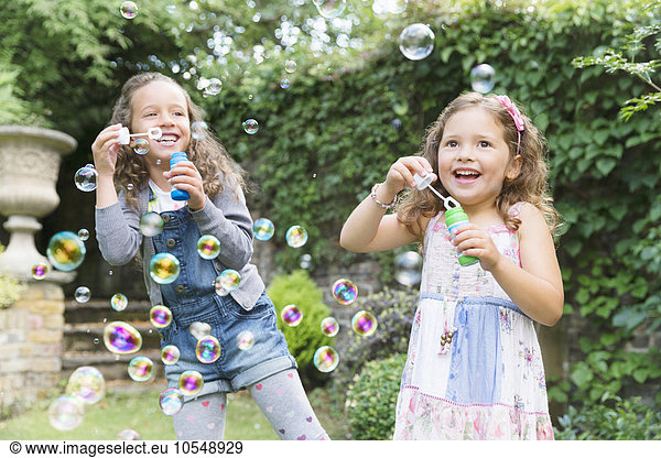 Carefree girls blowing bubbles in backyard