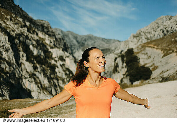 Carefree hiker smiling while standing with arms outstretched at Cares Trail in Picos De Europe National Park  Asturias  Spain