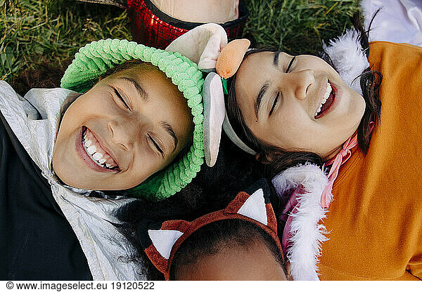 Carefree kids with eyes closed laughing while lying on grass at summer camp