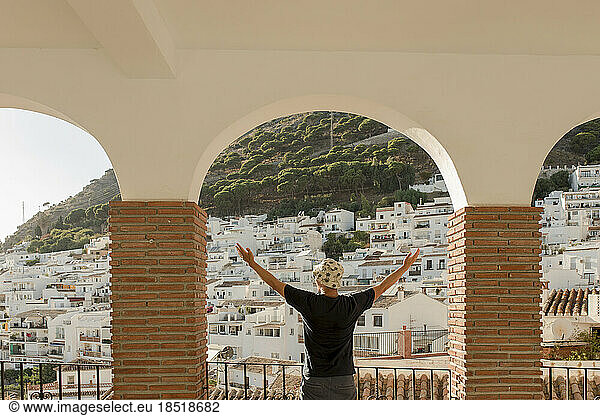 Carefree man with arms raised standing under arch