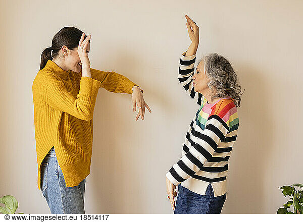 Carefree mother and daughter dancing by wall