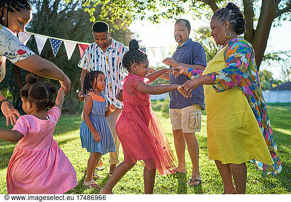 Carefree multigenerational family dancing in summer backyard