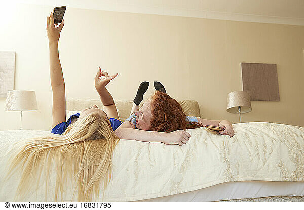 Carefree preteen girl friends taking selfie on bed