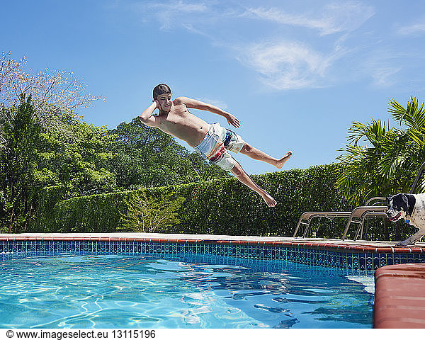 Carefree shirtless boy diving into swimming pool