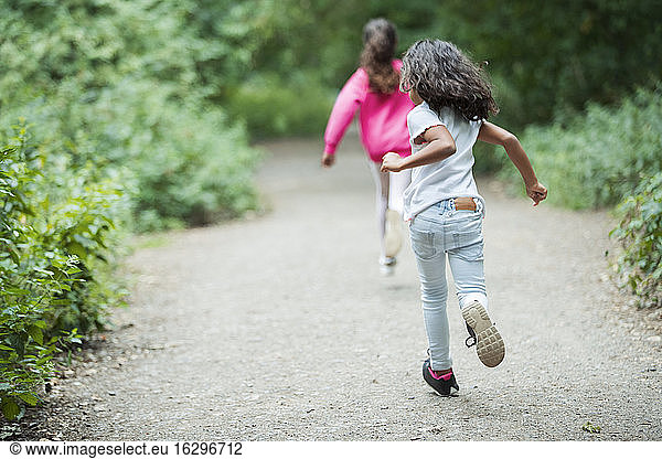 Carefree sisters running on park path