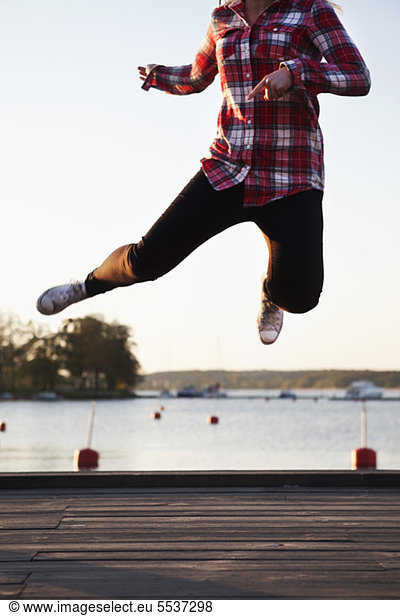 Carefree teenage girl jumping on pier