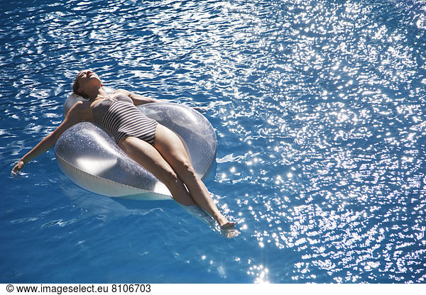 Carefree woman floating on inflatable ring in swimming pool
