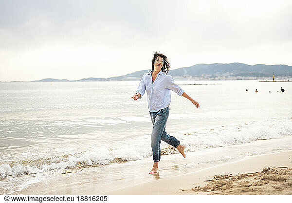Carefree woman running near shore at beach