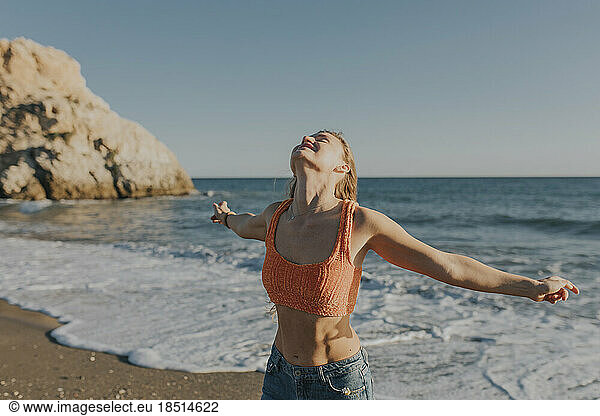 Carefree woman standing at beach on sunny day