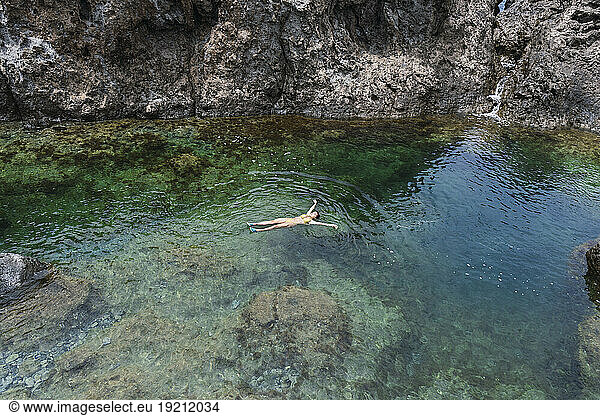 Carefree woman swimming in sea near rocks