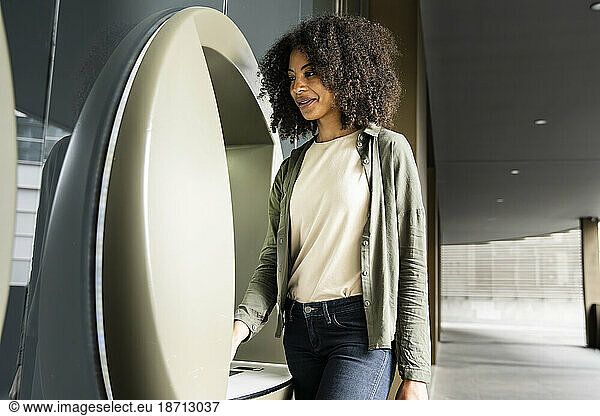 Carefree woman using an ATM machine.