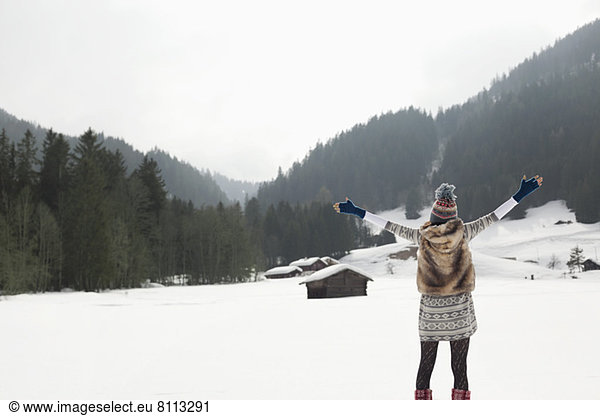 Carefree woman with arms outstretched in snowy field