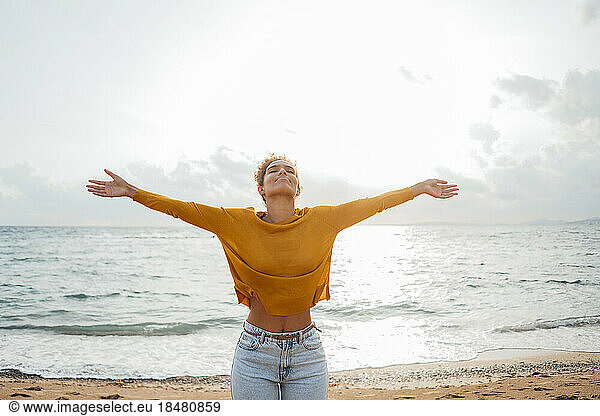 Carefree woman with arms outstretched on shore at beach