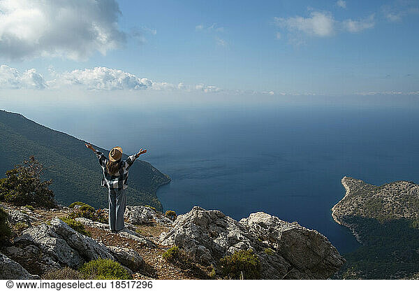 Carefree woman with arms outstretched standing on cliff