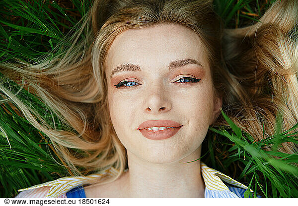 Carefree young blond woman lying in grass and enjoying summer time