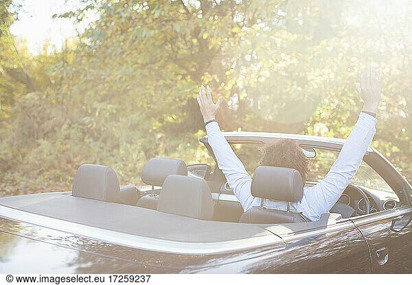 Carefree young man in convertible in sunny autumn park