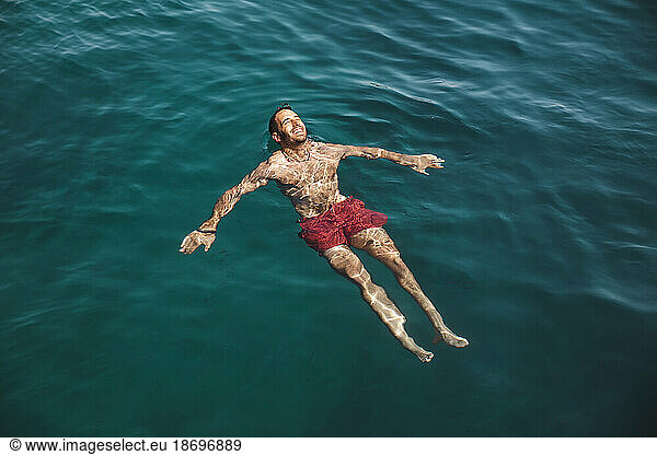 Carefree young man swimming in sea at vacation