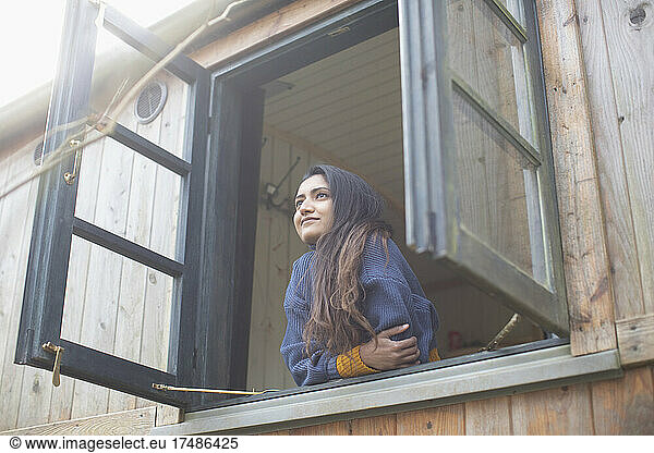 Carefree young woman looking out cabin window