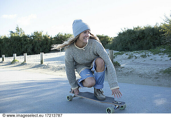 Carefree young woman skateboarding on beach path