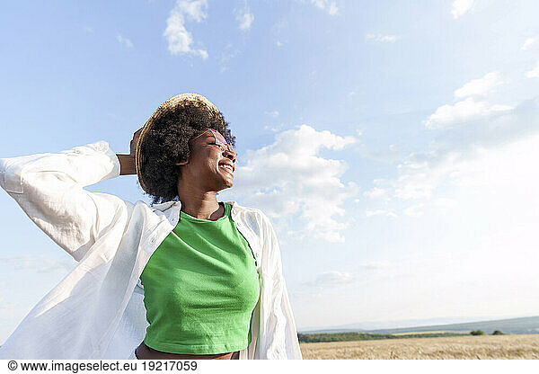 Carefree young woman wearing hat in field