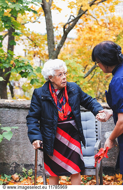 Caretaker assisting senior woman in park
