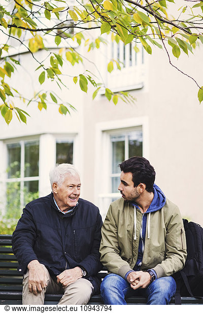 Caretaker communicating with senior man while sitting on bench
