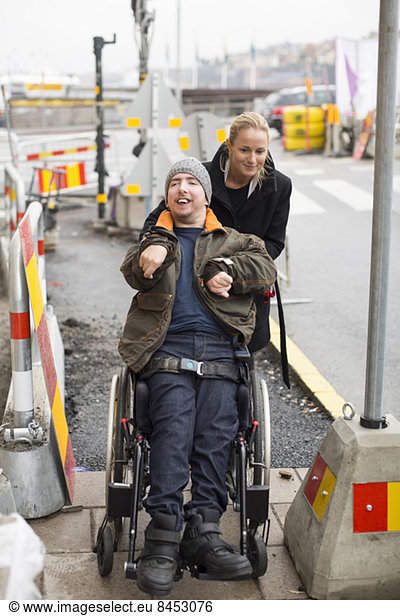 Caretaker pushing disabled man on wheelchair outdoors