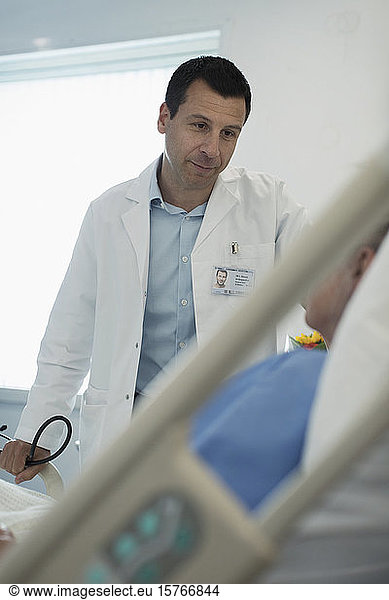 Caring male doctor making rounds  talking with patient in hospital room