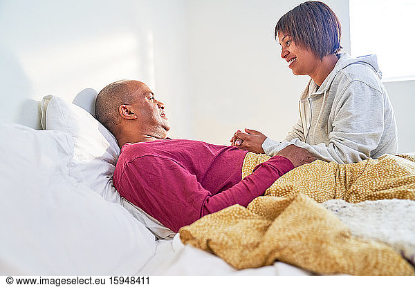 Caring wife checking on sick husband resting in bed