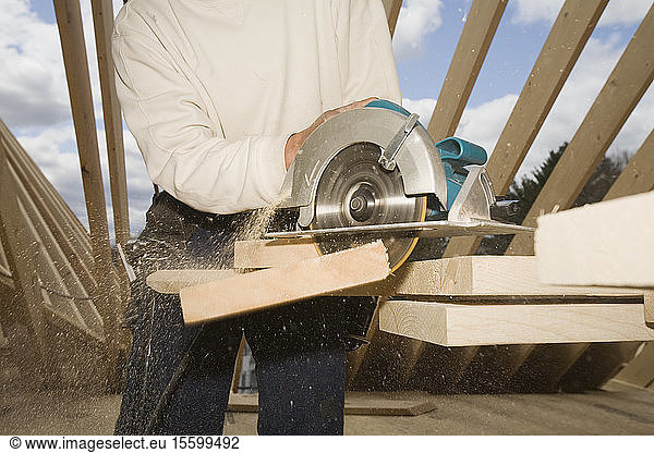 Carpenter cutting plank with a circular saw