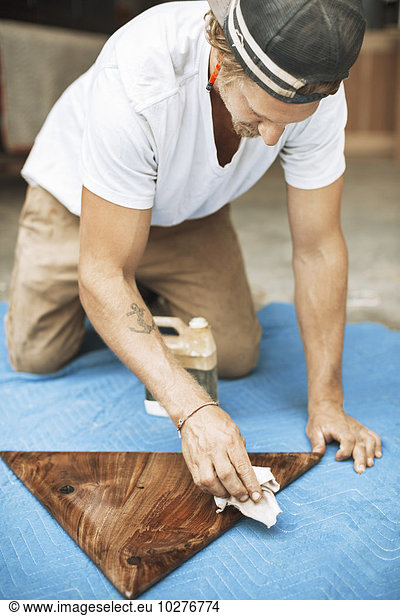 Carpenter polishing triangle shaped wood at workshop