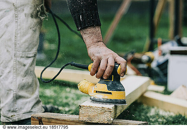 Carpenter polishing wood with sander