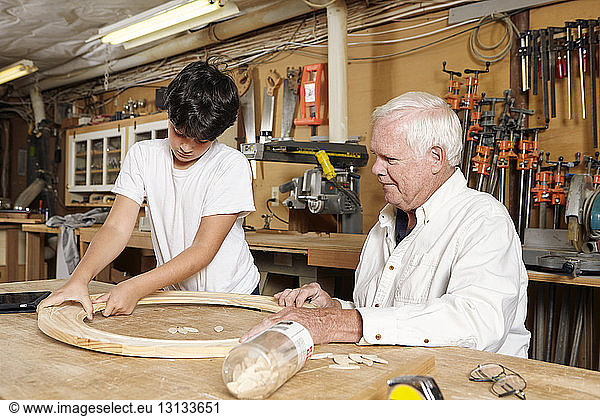 Carpenter teaching boy in workshop