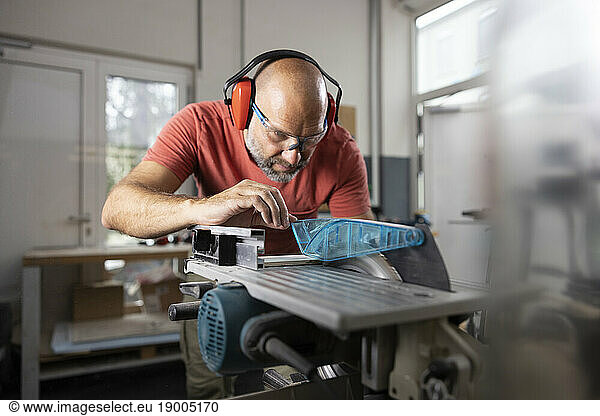 Carpenter wearing ear protectors working at workshop